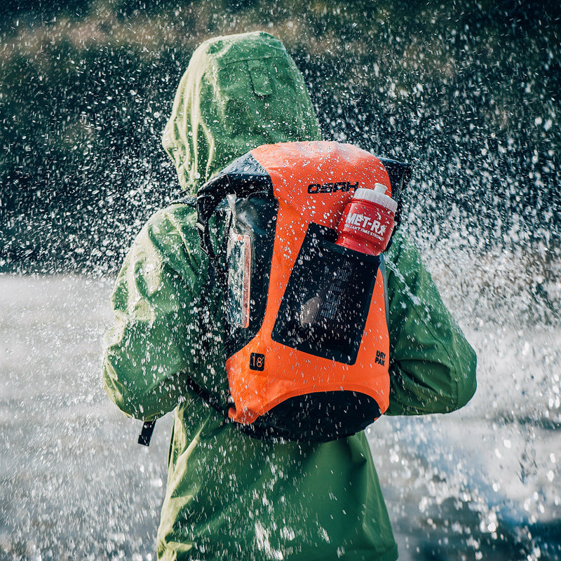 Person wearing a green raincoat with an orange backpack in a snowy environment